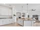 Open-concept kitchen featuring white cabinets, stainless appliances, pendant lighting, and island seating overlooking the living area at 15344 Serene Shores Loop, Bradenton, FL 34211