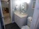 Bathroom with white vanity, black tile floor, and a round mirror above the sink at 1801 Gulf N Dr # 207, Bradenton Beach, FL 34217