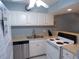 Kitchen view showing white appliances, stainless sink, and white cabinets, with neutral countertops at 1801 Gulf N Dr # 207, Bradenton Beach, FL 34217