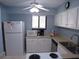 Kitchen view featuring white appliances, blue walls, tile floors, and a bright, windowed space at 1801 Gulf N Dr # 207, Bradenton Beach, FL 34217