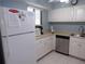 Kitchen view showcasing white cabinets, stainless steel dishwasher, tile floors, and neutral countertops at 1801 Gulf N Dr # 207, Bradenton Beach, FL 34217
