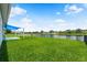 View of the home's spacious backyard with a black fence overlooking a tranquil pond and neighboring homes at 2347 123Rd E Pl, Parrish, FL 34219