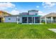View of the home's backyard featuring lush green grass and a covered patio with solar panels on the roof at 2347 123Rd E Pl, Parrish, FL 34219