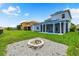Backyard featuring a cozy stone fire pit, lush green grass, and a covered patio in a fenced yard at 2347 123Rd E Pl, Parrish, FL 34219