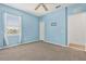 Bedroom with carpet, blue walls, window with blinds, ceiling fan, and an adjacent door at 2347 123Rd E Pl, Parrish, FL 34219