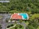 Aerial view of a community pool with palm trees, lounge chairs, and a stylish red-tiled roof building at 2347 123Rd E Pl, Parrish, FL 34219