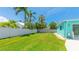 Expansive backyard with lush green lawn, privacy fence, and tropical palm trees create a serene outdoor retreat at 2713 Avenue C, Holmes Beach, FL 34217