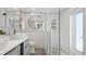 Bathroom with white subway tile walls, round mirror, vessel sinks and a glass enclosed shower at 2713 Avenue C, Holmes Beach, FL 34217