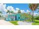 Charming turquoise home featuring a beautiful flowering tree, white rock landscaping, and a sunny Florida sky at 2713 Avenue C, Holmes Beach, FL 34217