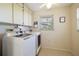 Bright laundry room featuring a washer, dryer, storage cabinets, and window at 2807 Coral Way, Punta Gorda, FL 33950