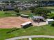 Aerial view of a well-maintained baseball field and sheltered seating areas with lush green surroundings at 305 Siena Vista Pl, Sun City Center, FL 33573