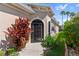 Charming front entrance with an arched doorway, colorful plants, and a well-maintained garden at 305 Siena Vista Pl, Sun City Center, FL 33573