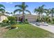 Charming single-story home featuring a manicured lawn, colorful flower beds, and a welcoming two-car garage at 305 Siena Vista Pl, Sun City Center, FL 33573