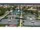 Aerial view showcases numerous tennis courts perfect for enthusiasts, surrounded by verdant landscaping and mature trees at 305 Siena Vista Pl, Sun City Center, FL 33573