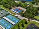 Aerial view of well-maintained tennis courts near a pond, surrounded by lush greenery, providing a picturesque setting at 305 Siena Vista Pl, Sun City Center, FL 33573