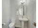 Elegant half bathroom featuring a pedestal sink, oval mirror, and modern lighting fixture at 4322 Marina View Way, Cortez, FL 34215