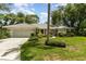 Charming single-story home boasts a tile roof, manicured lawn, and vibrant landscaping under a blue sky at 4353 Indian Point Trl, Sarasota, FL 34238