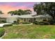 Charming single-story home boasts a tile roof, manicured lawn, and vibrant landscaping under a colorful sunset at 4353 Indian Point Trl, Sarasota, FL 34238