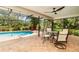 Screened-in pool area with brick flooring, ceiling fan, outdoor furniture, and lush green landscaping at 4353 Indian Point Trl, Sarasota, FL 34238