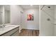 Well-lit bathroom featuring wood-look flooring, white cabinets, a flamingo art print, and a shower with white subway tile at 4425 Boxelder Avenue, Parrish, FL 34219