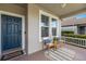 Cozy front porch with a blue front door, welcome mat, and two comfortable chairs and side table at 4617 Garden Arbor Way, Bradenton, FL 34203