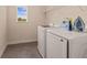 This laundry room includes both a washer and dryer with metal shelving above at 4617 Garden Arbor Way, Bradenton, FL 34203