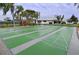 Active shuffleboard courts with palm trees and visitor benches in a bright sunny setting at 4832 Independence Dr, Bradenton, FL 34210