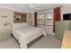 Cozy bedroom with a ceiling fan, bright window, and decorative wood-framed mirror on the wall at 519 Albee Farm Rd # 212, Venice, FL 34285