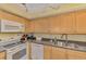 Well-equipped kitchen with white appliances, light wood cabinetry, and granite countertops at 519 Albee Farm Rd # 212, Venice, FL 34285