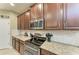 Close-up of a kitchen showcasing stainless steel appliances, granite countertops, and dark wood cabinets at 5307 65Th E Ter, Ellenton, FL 34222
