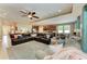 Open-concept living room featuring a large sectional sofa, ceiling fan, and a view into the kitchen at 5307 65Th E Ter, Ellenton, FL 34222