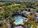 A stunning aerial view of the community pool and tennis courts nestled amongst lush greenery and mature trees at 5349 Everwood Run, Sarasota, FL 34235