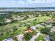 Aerial view of a home with a pool and patio, surrounded by lush landscaping and a golf course in the distance at 5349 Everwood Run, Sarasota, FL 34235