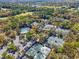 An aerial view showcasing a community swimming pool and tennis courts surrounded by lush greenery and a parking lot at 5349 Everwood Run, Sarasota, FL 34235