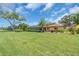 Expansive backyard with lush green grass, mature trees, and a covered patio area perfect for entertaining at 5349 Everwood Run, Sarasota, FL 34235