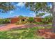 Inviting home featuring a red tile roof, arched entryway, mature trees, and lush landscaping at 5349 Everwood Run, Sarasota, FL 34235