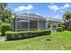 Landscaped backyard featuring a screened-in patio with lush green grass and trimmed hedges at 5508 Whitehead St, Bradenton, FL 34203