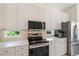 Modern kitchen with white cabinets, stainless steel appliances, and small windows with outdoor views at 5508 Whitehead St, Bradenton, FL 34203