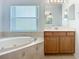 Bathroom with a corner soaking tub, vanity with cabinetry, and window for natural light at 6043 44Th E Ct, Bradenton, FL 34203
