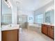 Bathroom showcasing double vanities, a glass-enclosed shower, and a separate soaking tub at 6043 44Th E Ct, Bradenton, FL 34203