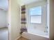 Bright bathroom featuring a white tub with a window and decorative shower curtain at 6043 44Th E Ct, Bradenton, FL 34203