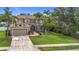 Two-story home featuring well-manicured lawn, mature trees, and a spacious driveway leading to a two-car garage at 6043 44Th E Ct, Bradenton, FL 34203