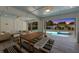 Covered outdoor living space with a dining table, lounge seating, and pool views at 616 Fern St, Anna Maria, FL 34216