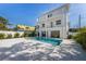 A luxurious pool area in a modern white two-story home with an outdoor living space on a sunny day at 616 Fern St, Anna Maria, FL 34216