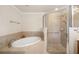 Bathroom featuring walk-in shower with glass door and soaking tub with beige tile surround at 6923 Grand Estuary Trl # 101, Bradenton, FL 34212