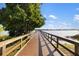 Scenic view along a wooden pier extending into a serene lake, surrounded by lush vegetation and a clear blue sky at 6923 Grand Estuary Trl # 101, Bradenton, FL 34212