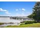 Lake view featuring a wooden pier extending into the calm water, set against a backdrop of lush greenery and blue sky at 6923 Grand Estuary Trl # 101, Bradenton, FL 34212