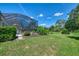 Backyard featuring well-manicured landscaping, a spacious lawn, and a glimpse of a screened-in pool area at 7302 Dunes Ct, Bradenton, FL 34202