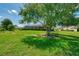Expansive backyard with green lawn, mature trees, and a view of the home's screened pool enclosure at 7302 Dunes Ct, Bradenton, FL 34202