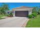 Two-car garage of a single-story home featuring a tile roof, landscaped yard, and concrete driveway at 7302 Dunes Ct, Bradenton, FL 34202